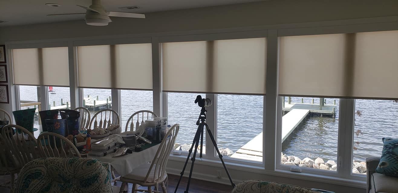 A living room with a view of the water and a camera on a tripod.
