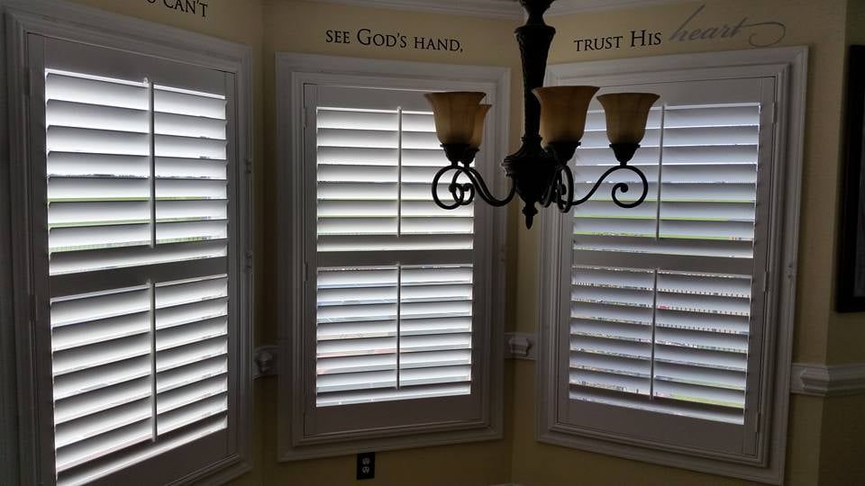 A room with a chandelier and shutters on the windows