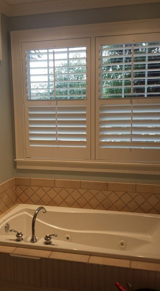 A bathroom with a jacuzzi tub and shutters on the windows.