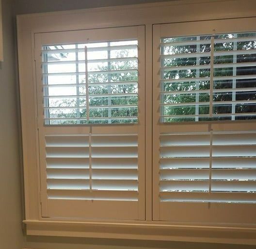 A window with shutters on it and a view of trees.