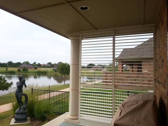 A view of a lake from a porch with shutters