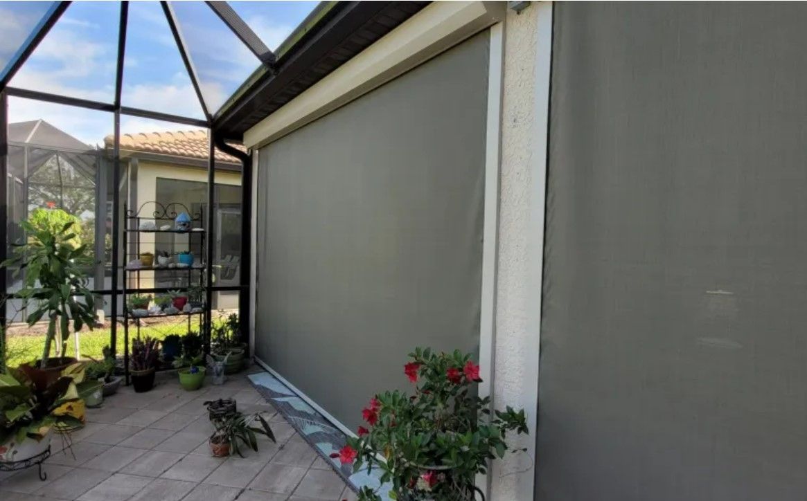 A screened in porch with a gray screen on the side of a house.