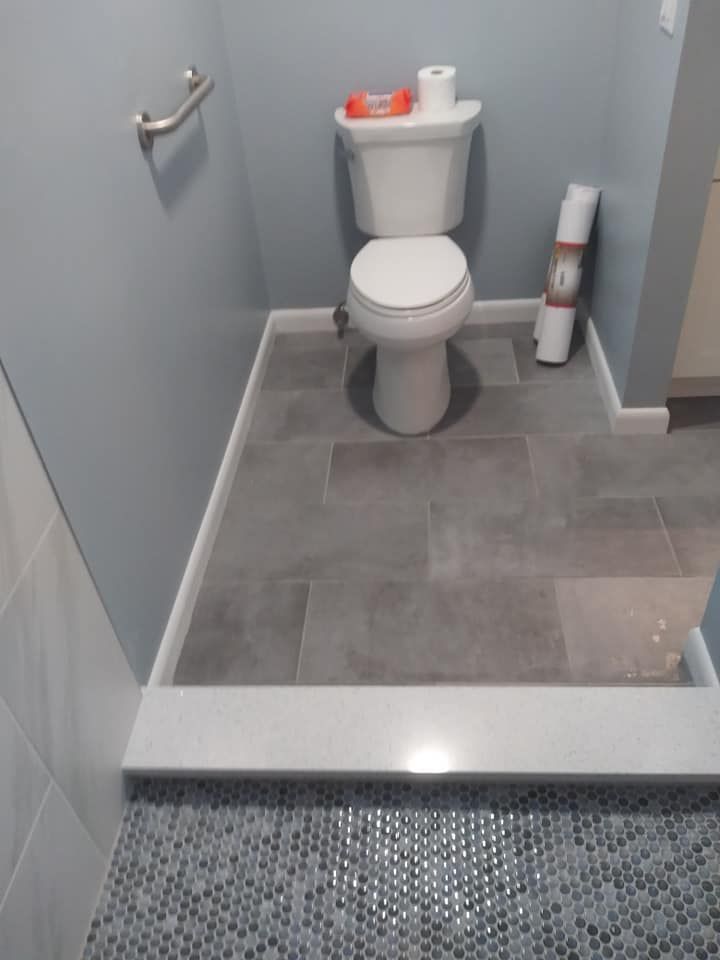 A toilet is sitting on a tiled floor in a bathroom.