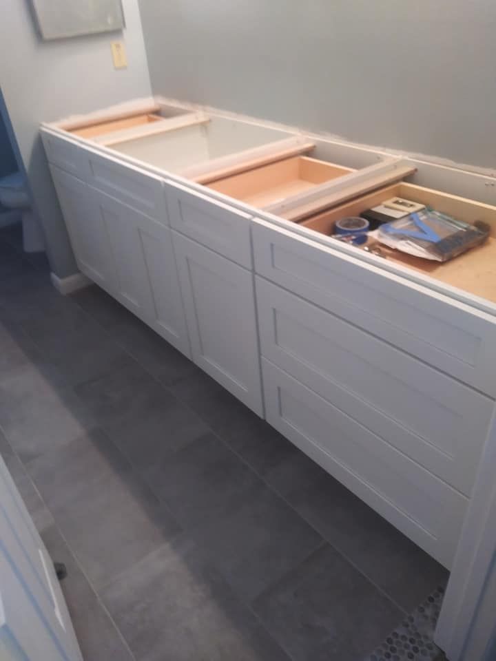 A bathroom vanity is being built with white cabinets and wooden drawers