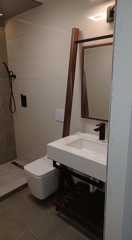 A bathroom with a sink , toilet , shower and mirror.
