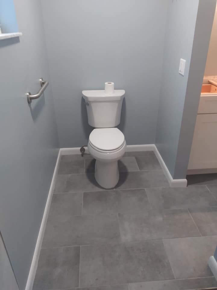A toilet is sitting on a tiled floor in a bathroom.