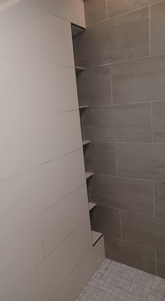 A bathroom with a walk in shower and shelves on the wall.