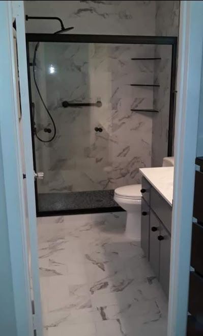 A bathroom with a toilet , sink and shower.