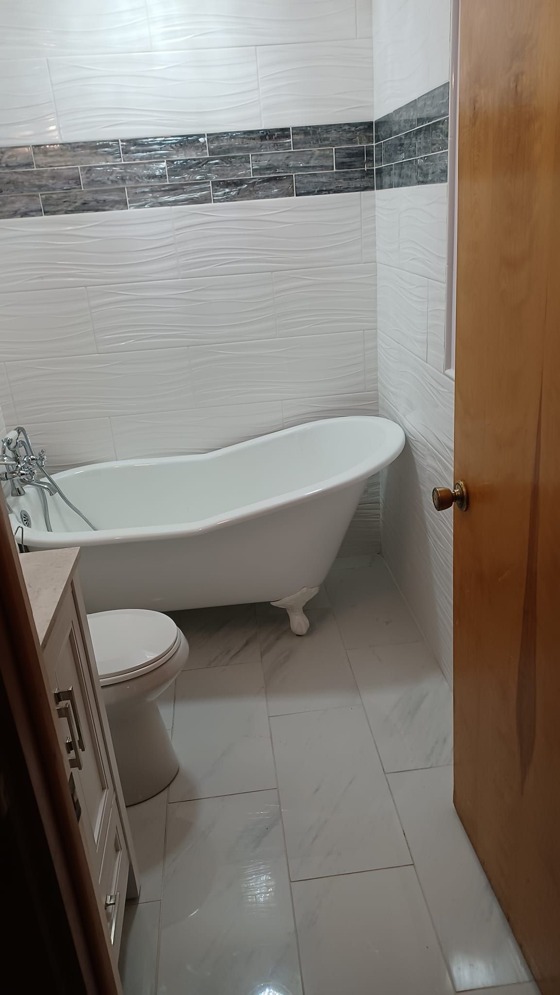 A bathroom with a bathtub , toilet , and cabinet.