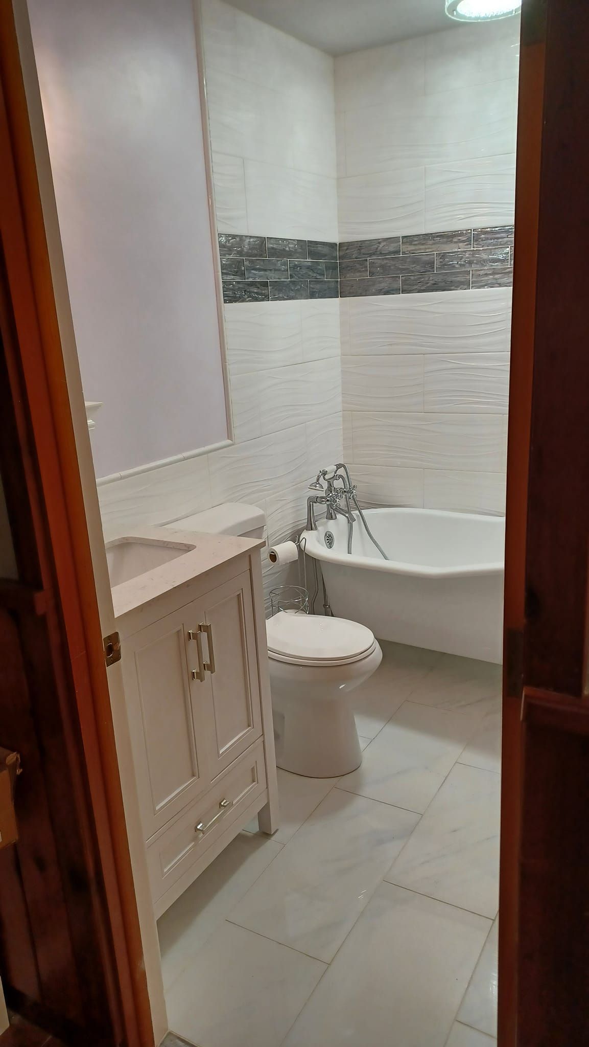 A bathroom with a toilet , sink , tub and mirror.