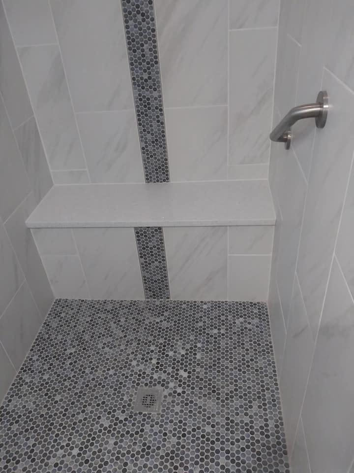 A shower with a bench and a shower head.