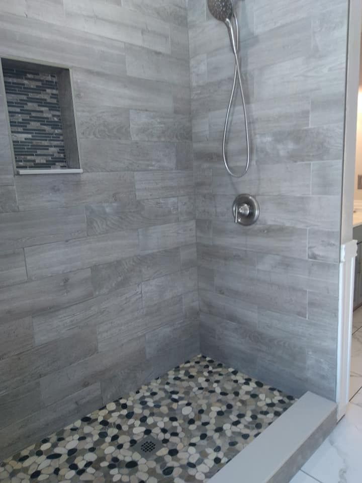 A walk in shower with a tiled floor and a shower head.