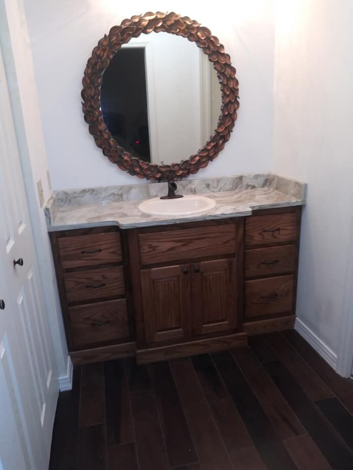 A bathroom vanity with a round mirror above it