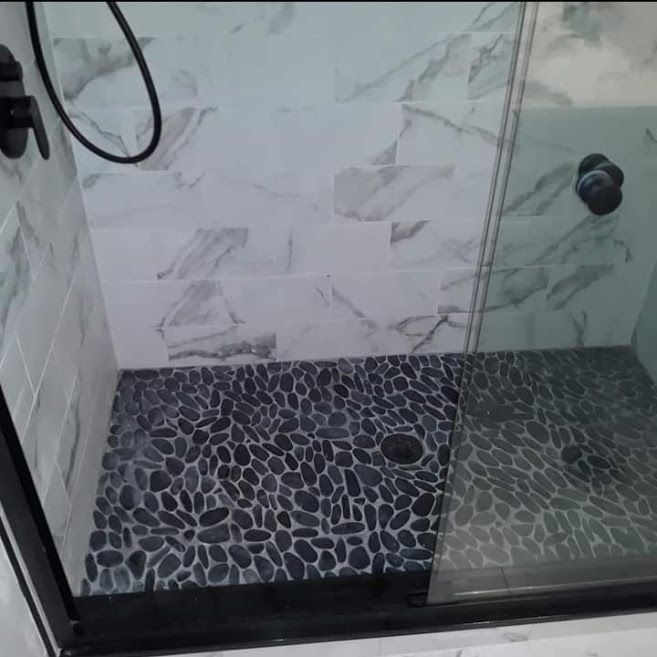 A shower with a tiled floor and a glass door