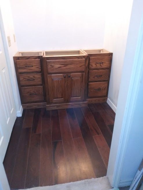 A bathroom with wooden cabinets and drawers and a sink.