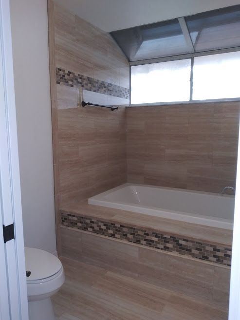 A bathroom with a tub , toilet and window