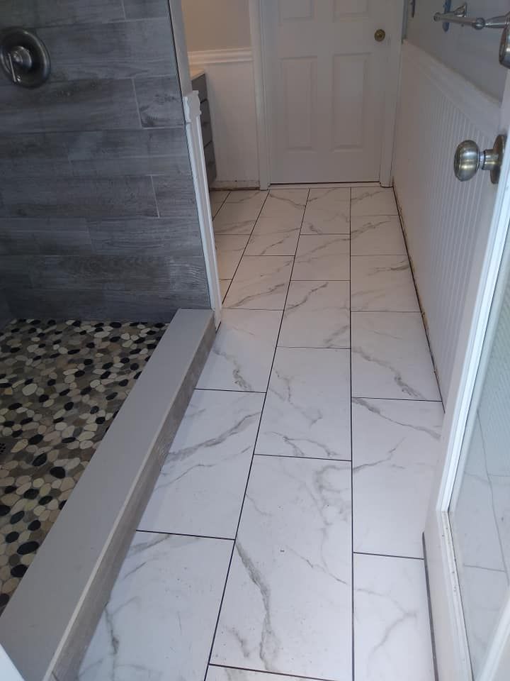 A bathroom with white tiles and a walk in shower.