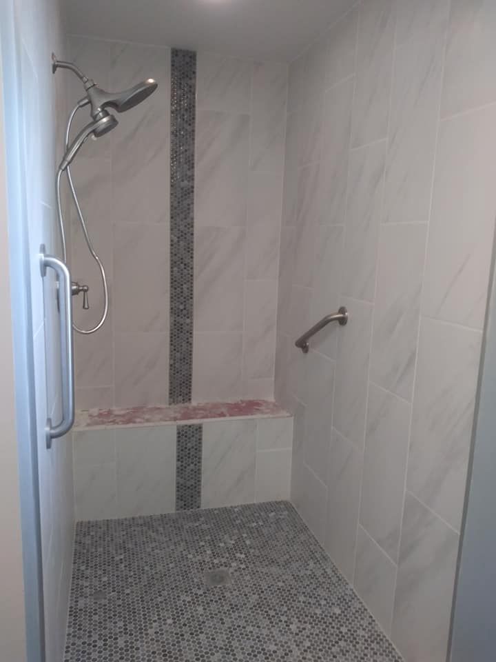 A walk in shower with a tiled floor and a shower head.