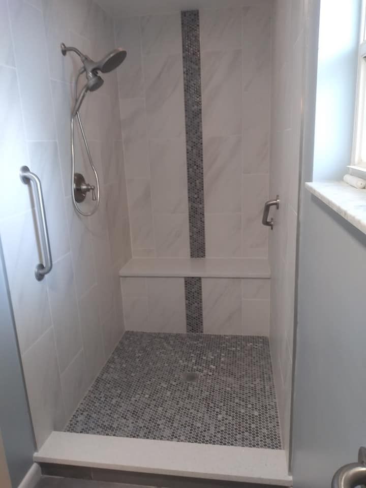 A shower with a bench and a shower head in a bathroom.