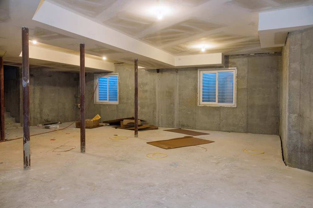 an empty basement with concrete walls and windows .