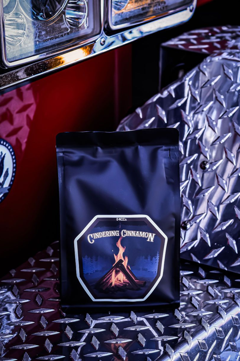 Black coffee bag with campfire label on a diamond plate surface next to a red vehicle.