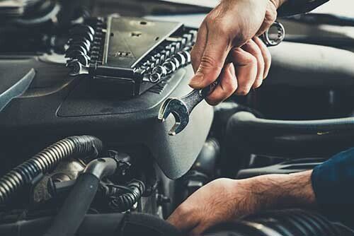 Mechanic using a wrench to work on a car engine.