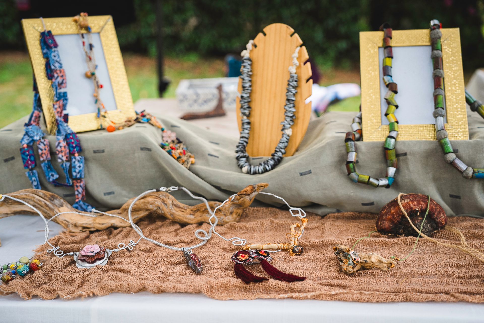 Esposizione di gioielli: collane, orecchini e braccialetti su un tavolo in un mercato all'aperto, con perline colorate e texture.
