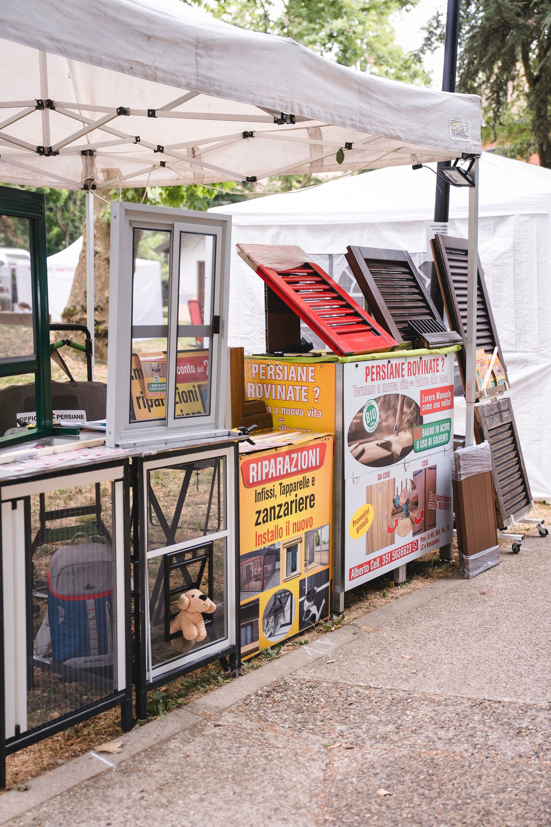 Uno stand di un venditore in un mercato all'aperto che vende finestre, persiane e insegne d'epoca.