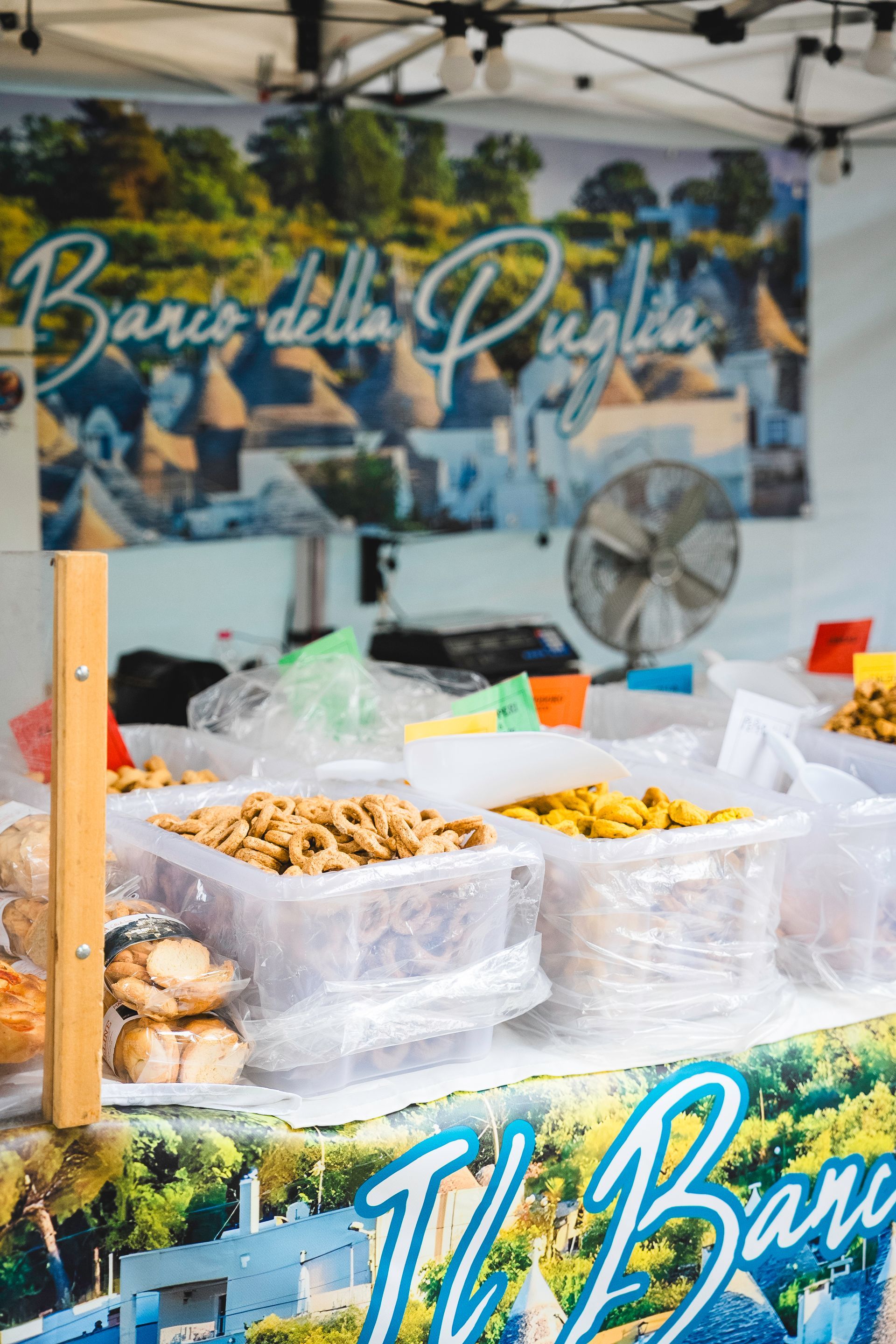 Una bancarella di cibo che vende noci e dolci in Puglia, Italia, con sullo sfondo i trulli.