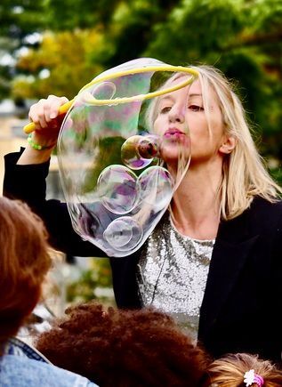 Donna che soffia bolle giganti sotto gli occhi dei bambini.