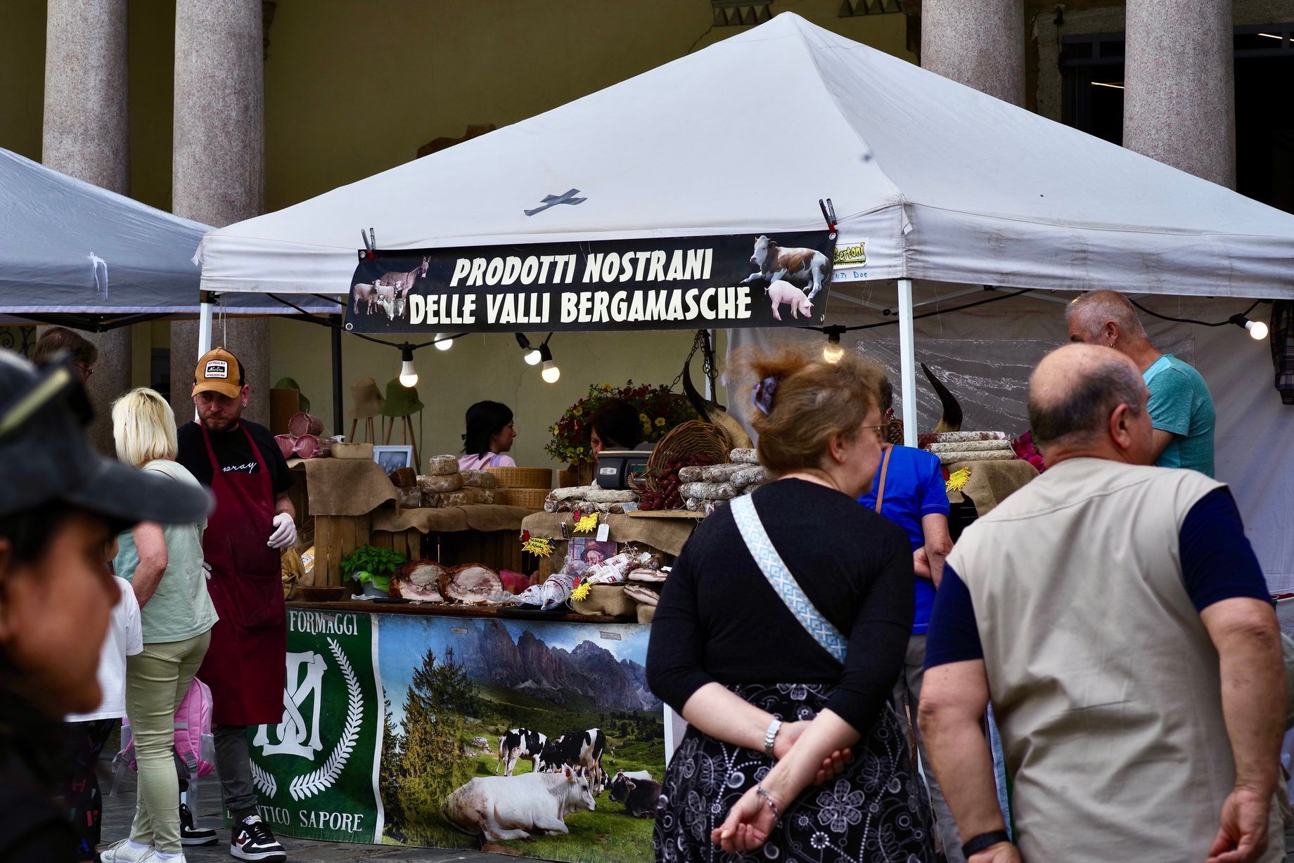 Bancarella di prodotti alimentari; la gente curiosa e fa acquisti.