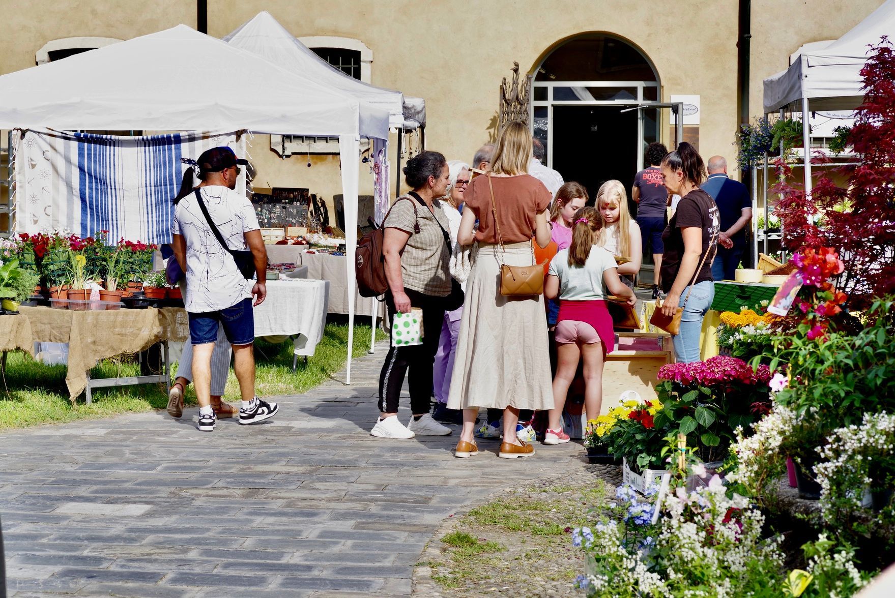 Nelle giornate di sole la gente curiosa tra le bancarelle del mercato all'aperto, dove si vendono piante e altri prodotti.