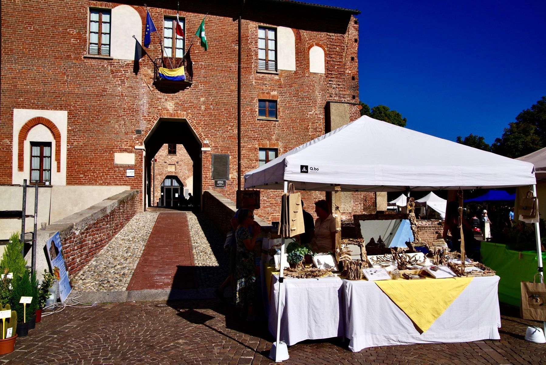 Una bancarella di artigianato di fronte a un edificio in mattoni con un ingresso ad arco in una giornata di sole.