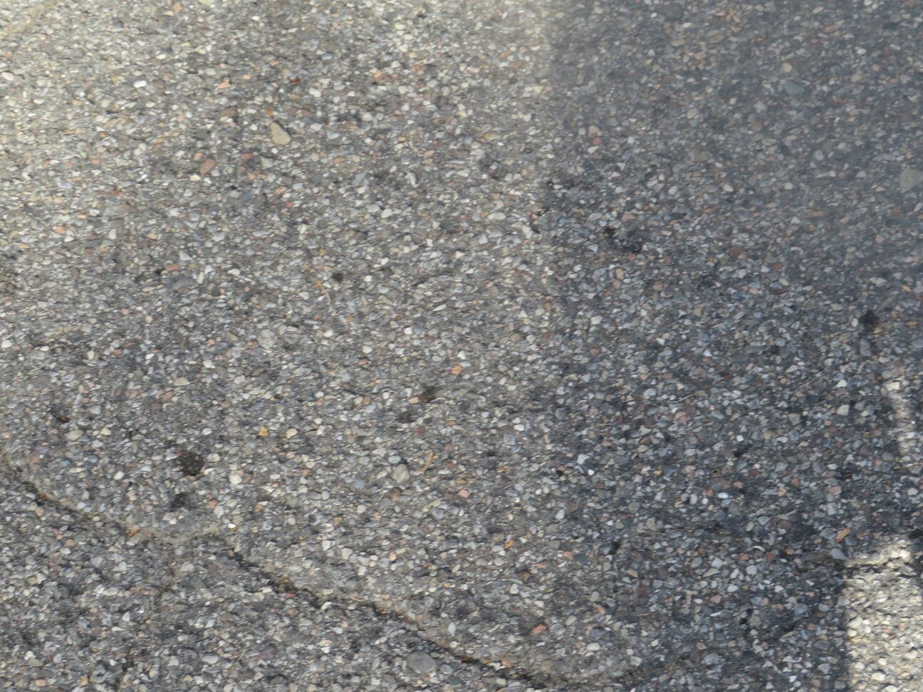 Primo piano della superficie ruvida dell'asfalto grigio.