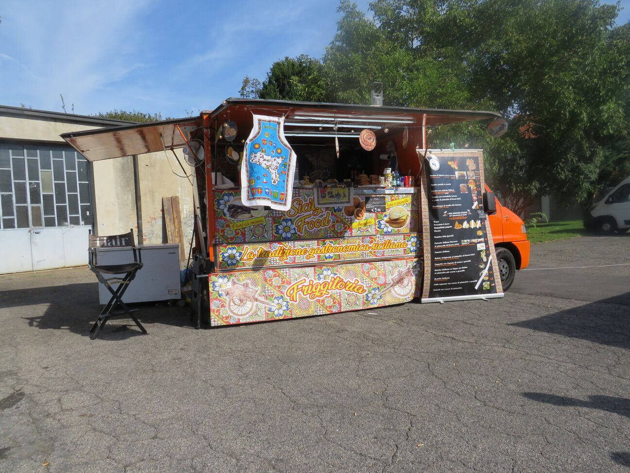 Camion di cibo arancione con tendalino aperto, che espone il menu e il cibo.