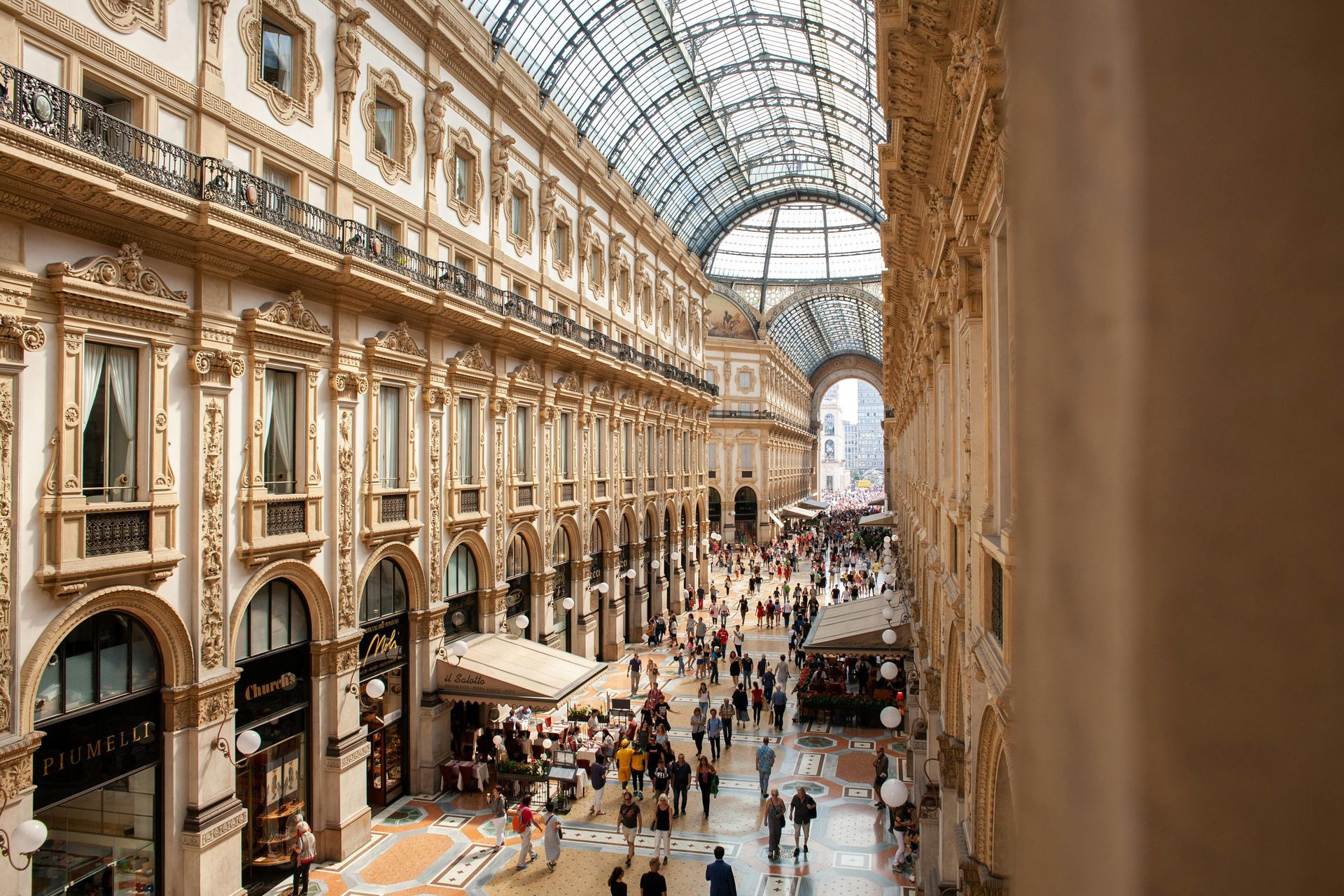 All'interno della Galleria Vittorio Emanuele II a Milano, Italia, brulicante di gente e negozi sotto una cupola di vetro.