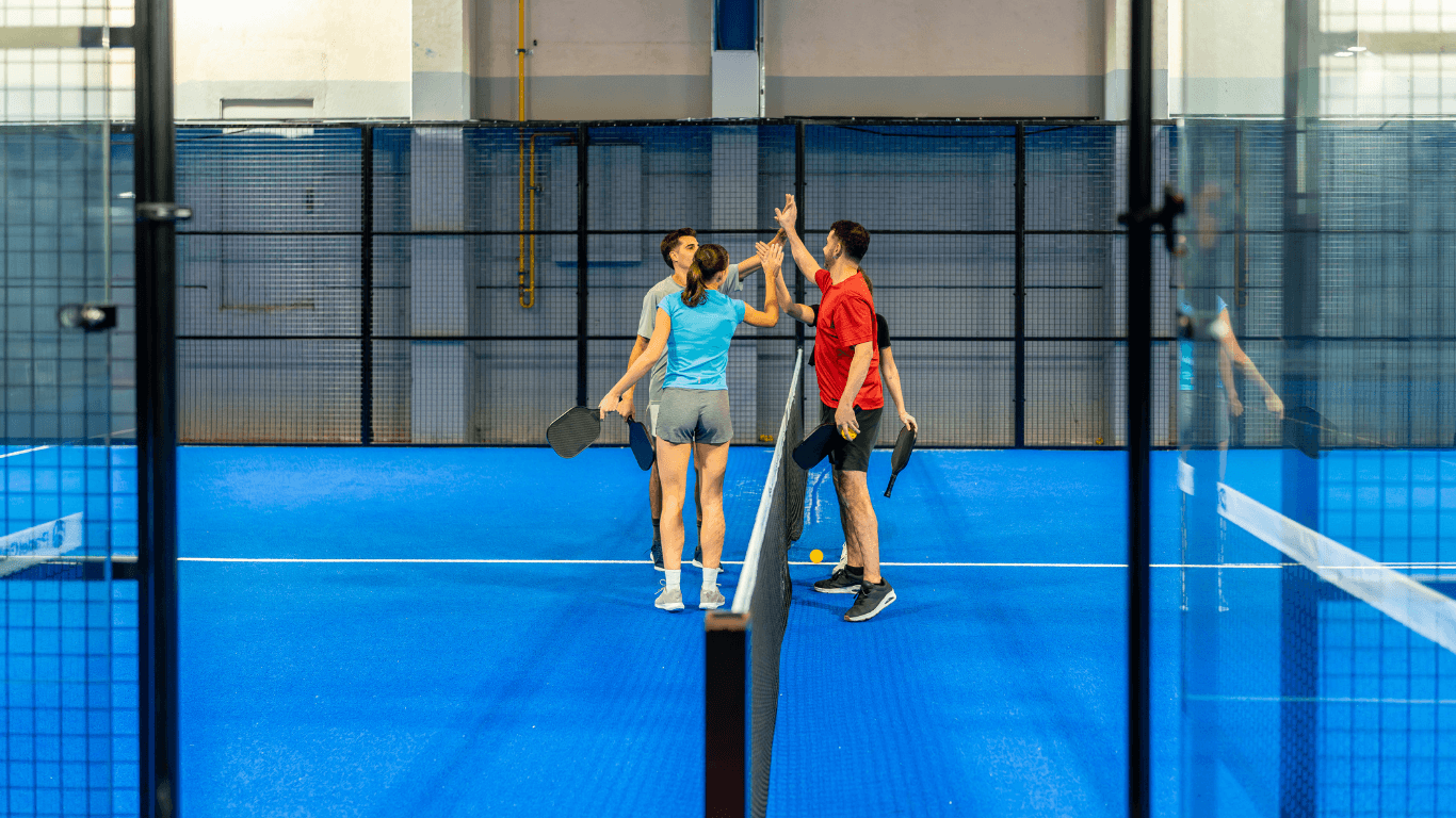 Players standing on a modern indoor court with glass walls and blue flooring after a court installation service in Chandler, A