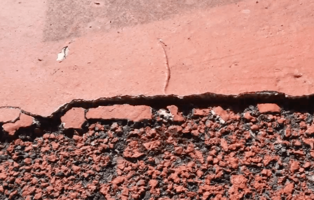 Close-up of a damaged sport court surface with deep cracks before restoration and court installation service in Chandler, AZ