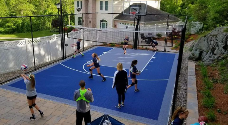 Residential backyard basketball court with players enjoying a newly installed blue playing surface during a court installation service in Chandler, AZ