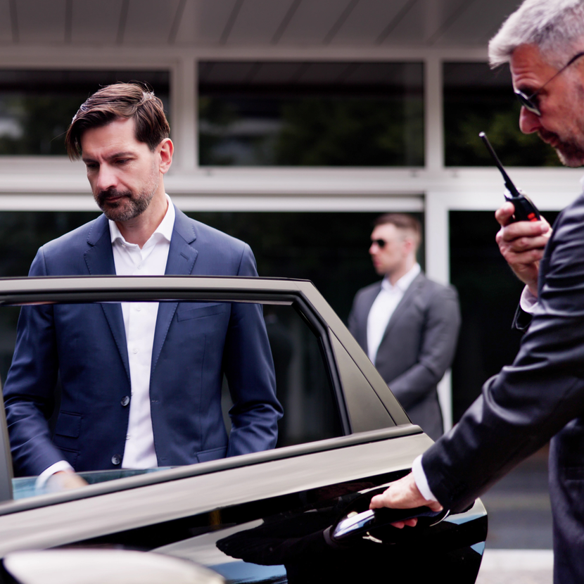 A man in a suit is opening the door of a car