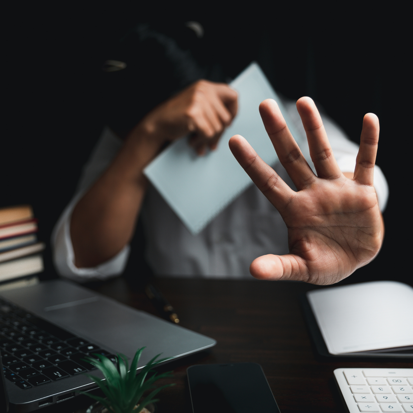 A person is sitting at a desk with a laptop and a palm up
