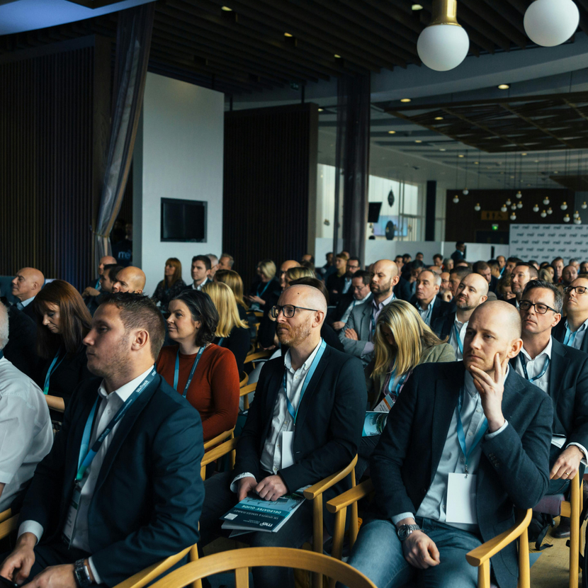 A large group of people are sitting in chairs watching a presentation