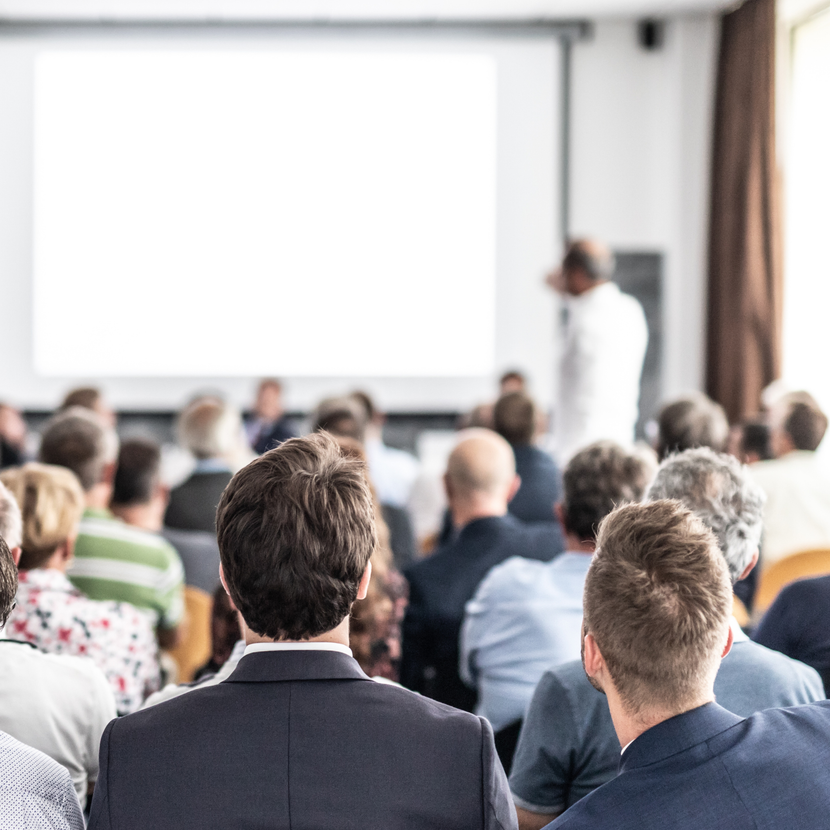 A group of people are sitting in a room watching a presentation.