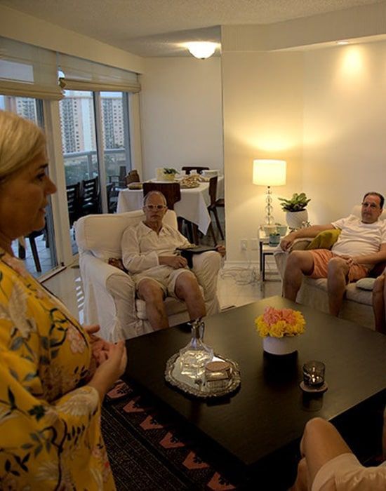Un grupo de personas están sentadas alrededor de una mesa en una sala de estar.