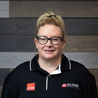 A woman wearing glasses and a black polo shirt is smiling for the camera.