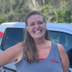 a woman in a tank top is smiling in front of a truck