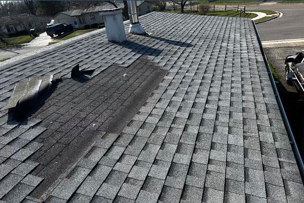 a roof with a lot of damaged shingles and a chimney on it