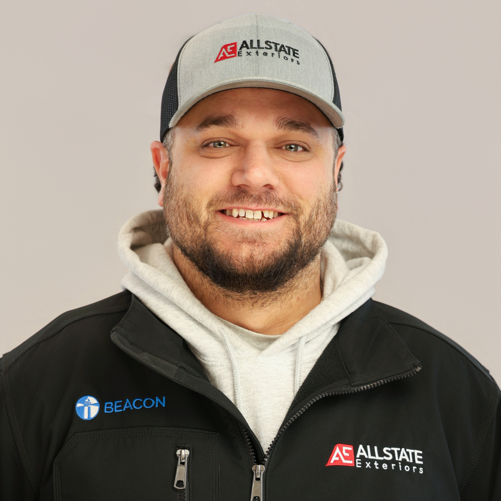 A man with a beard is wearing a gray hat and hoodie.