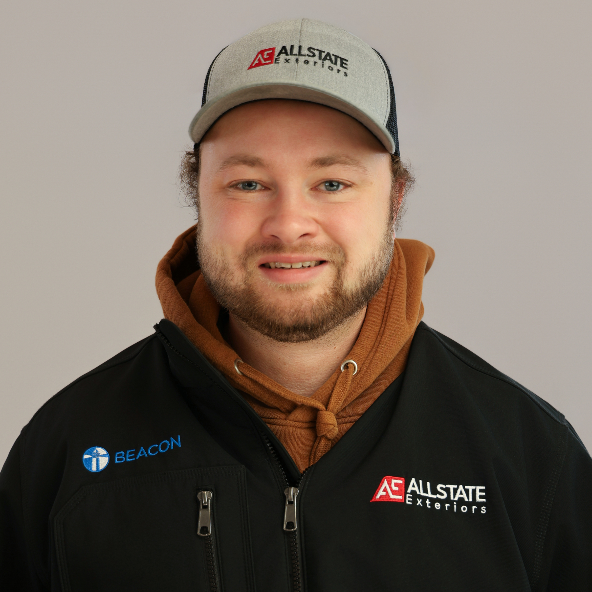 A man with his arms crossed is standing in front of a field of tall grass.