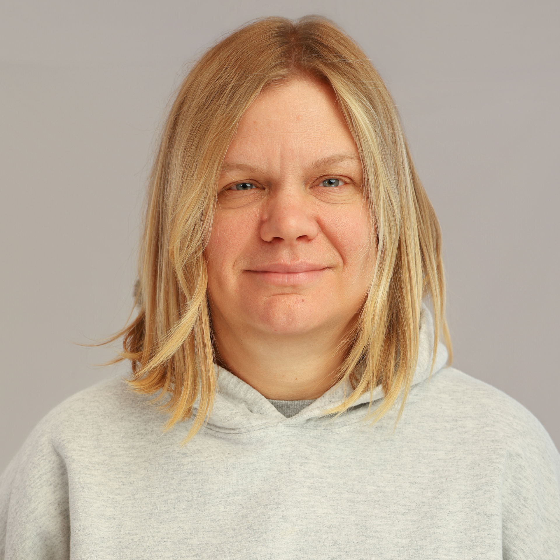 A man with a beard is standing in a field with his arms crossed and smiling.